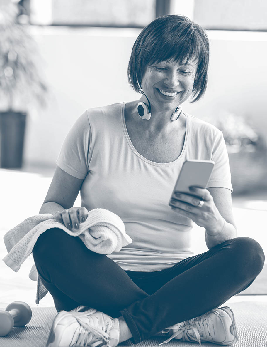 Older,Woman,Using,Smartphone,After,Sports,Training,Sitting,Indoors,At